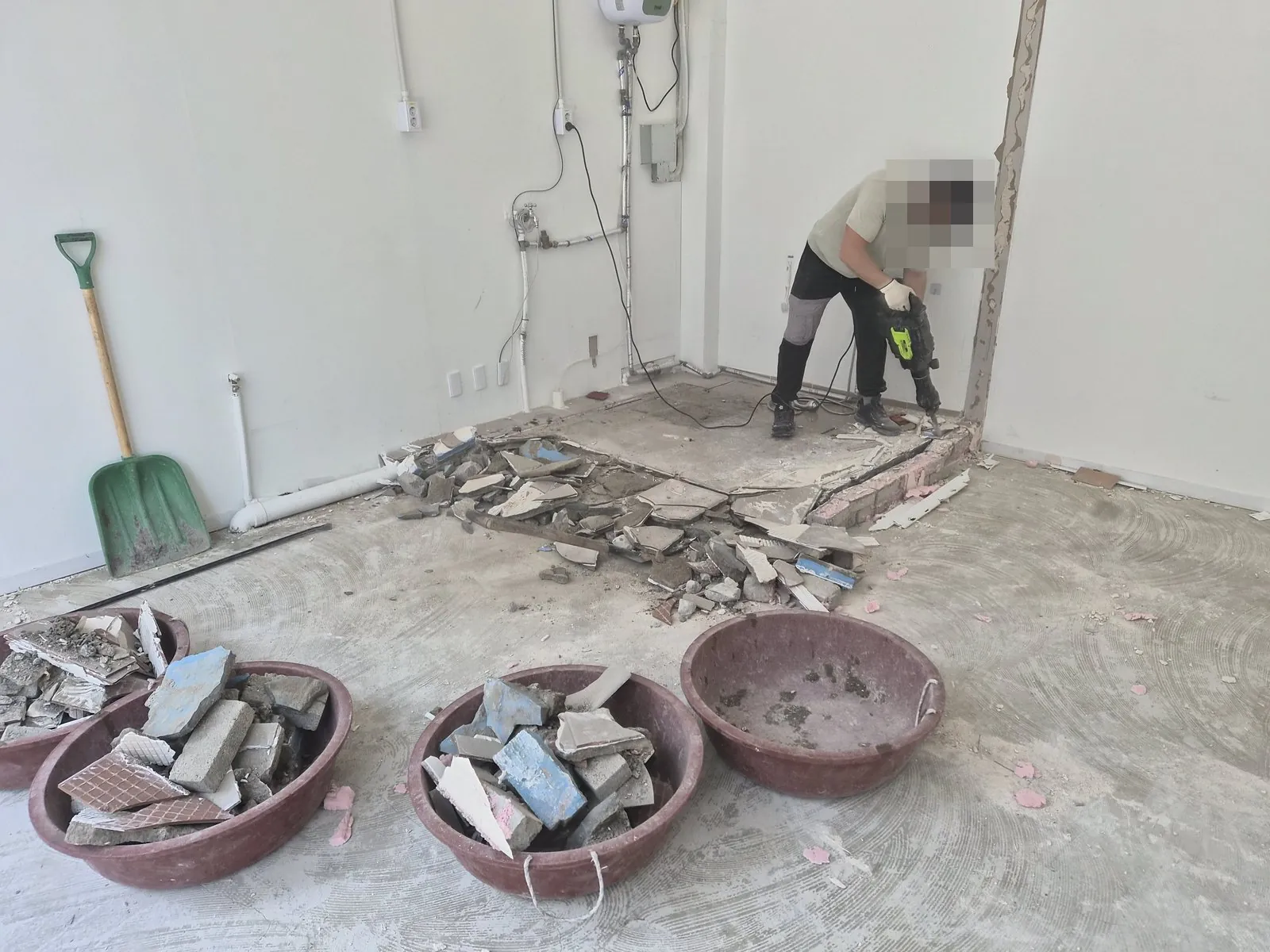 핸드 브레이커로 바닥 타일 단을 깨고 잔재를 고무 대야에 담는 작업