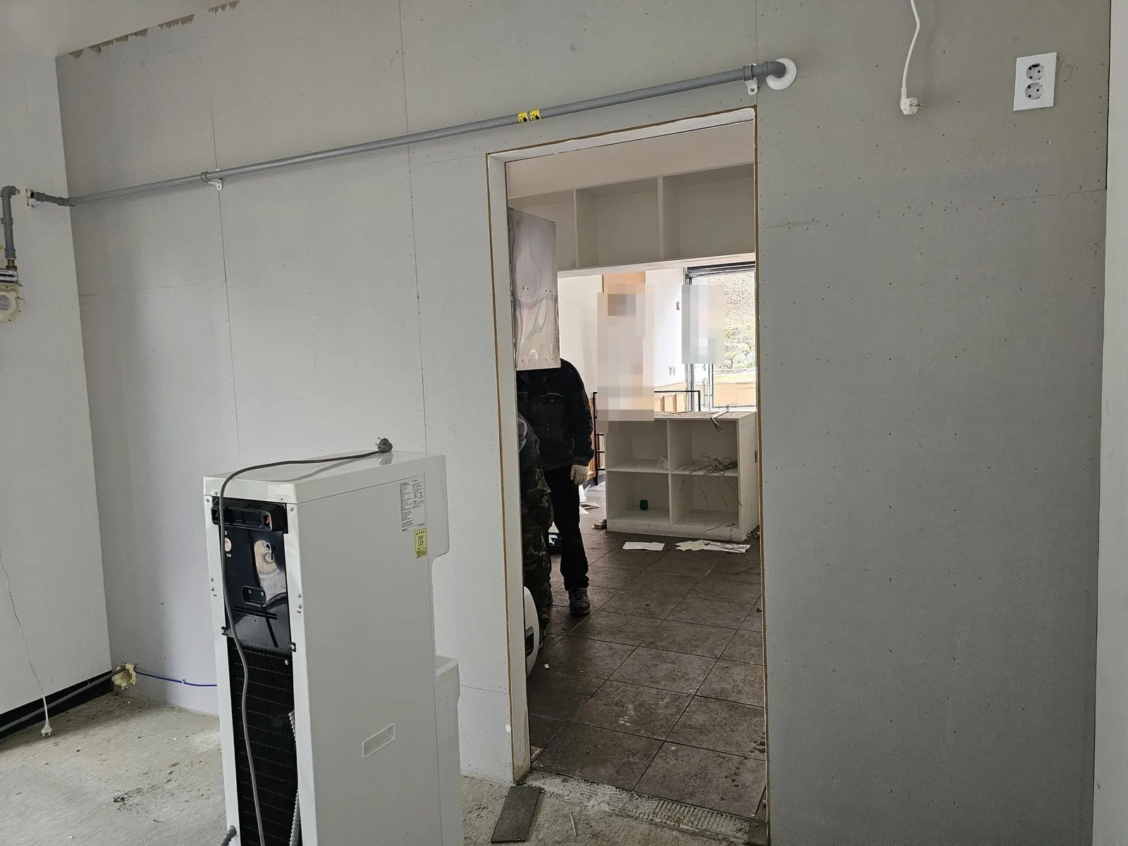 석고보드 벽 개구부 너머로 비워지는 매장과 정수기가 보임