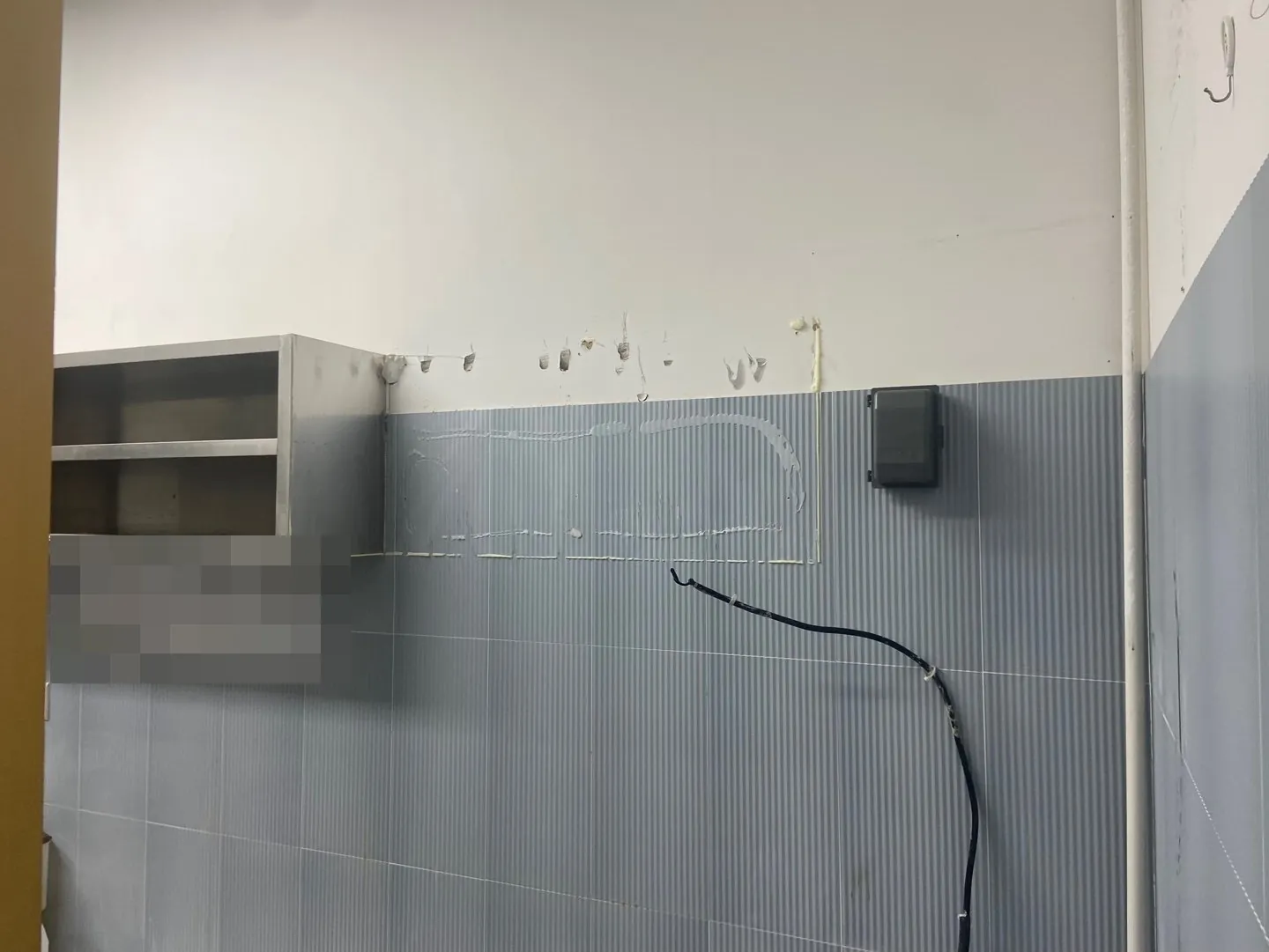주방 타일 벽에 선반장이 남아 있고 떼어낸 자국이 보인다.