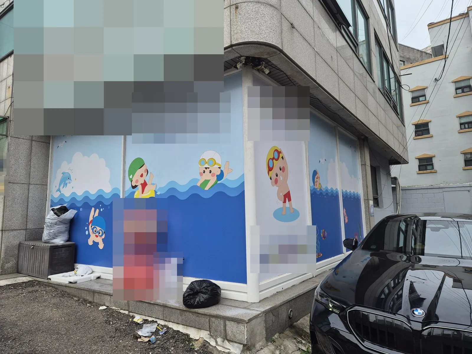 건물 모서리 외부 전면과 앞 바닥에 놓인 쓰레기 자루