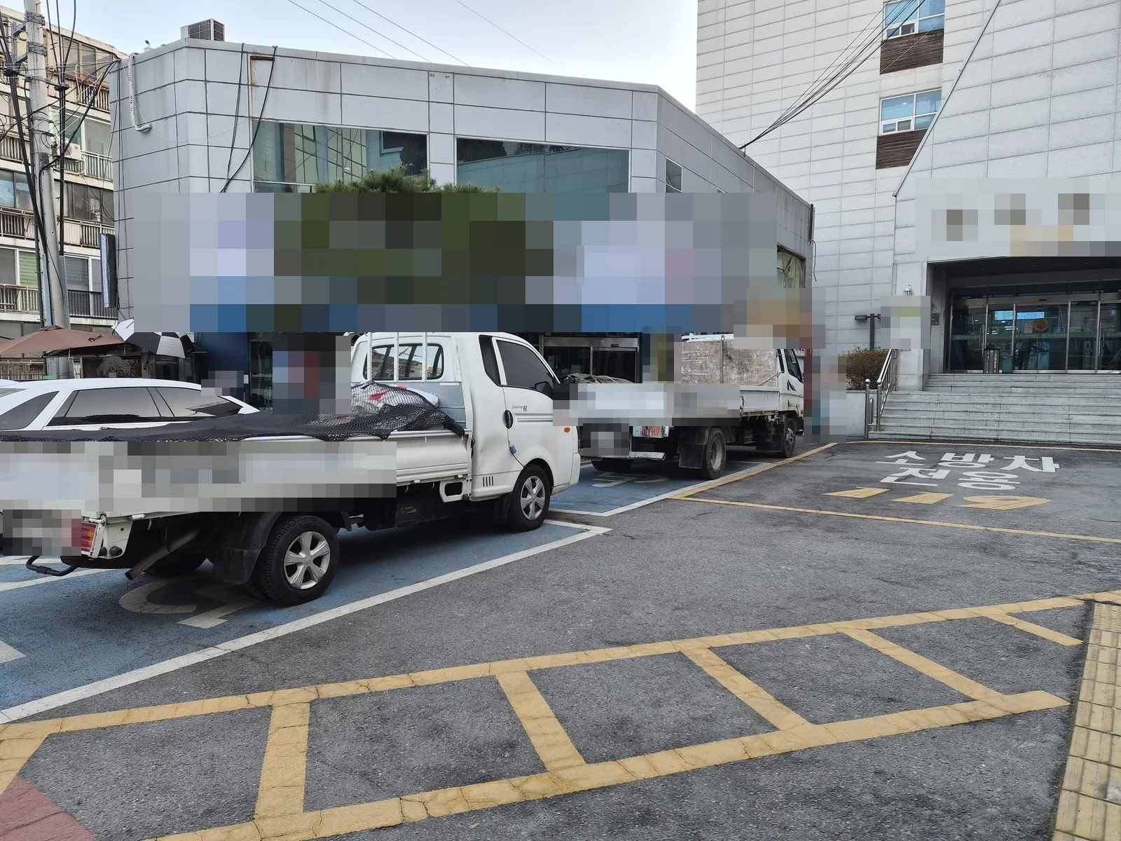 철거 화물차 두 대가 건물 앞 주차장에 서 있는 외부
