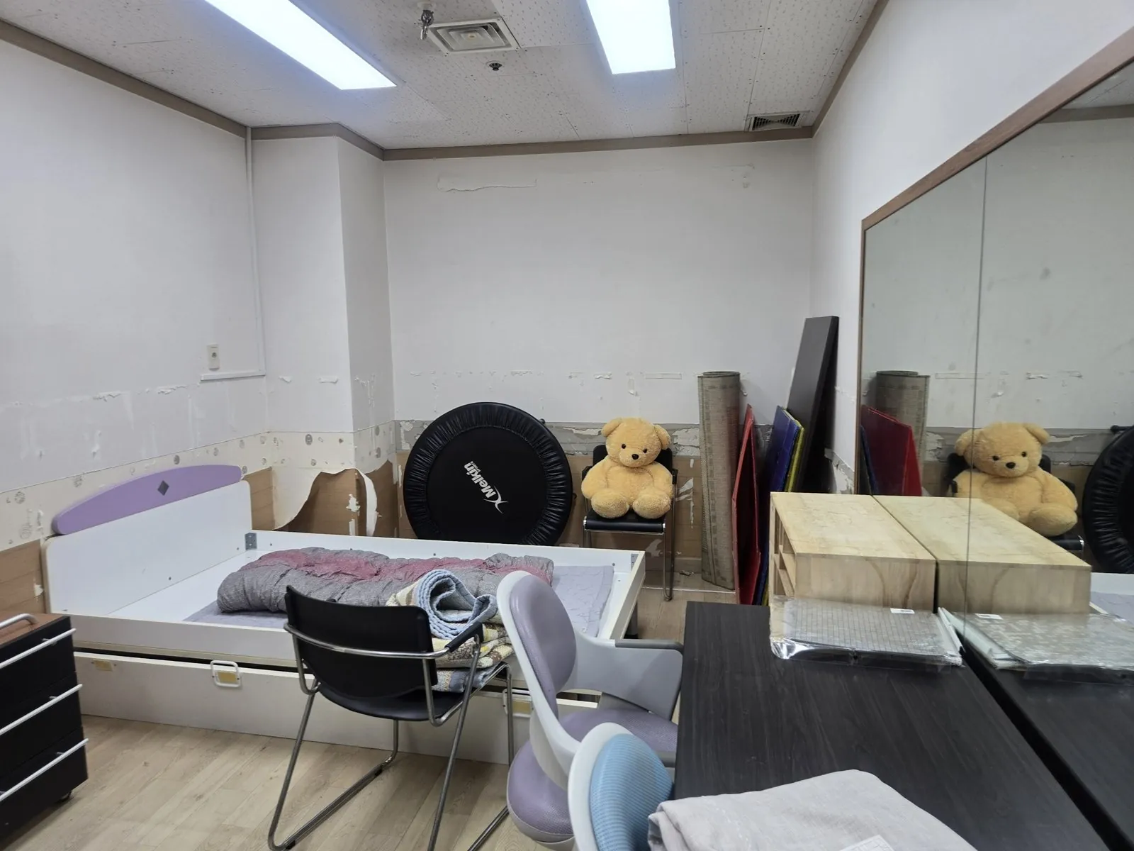 방에 침대와 책상이 남아 있고 벽 마감이 뜯겨 있다.