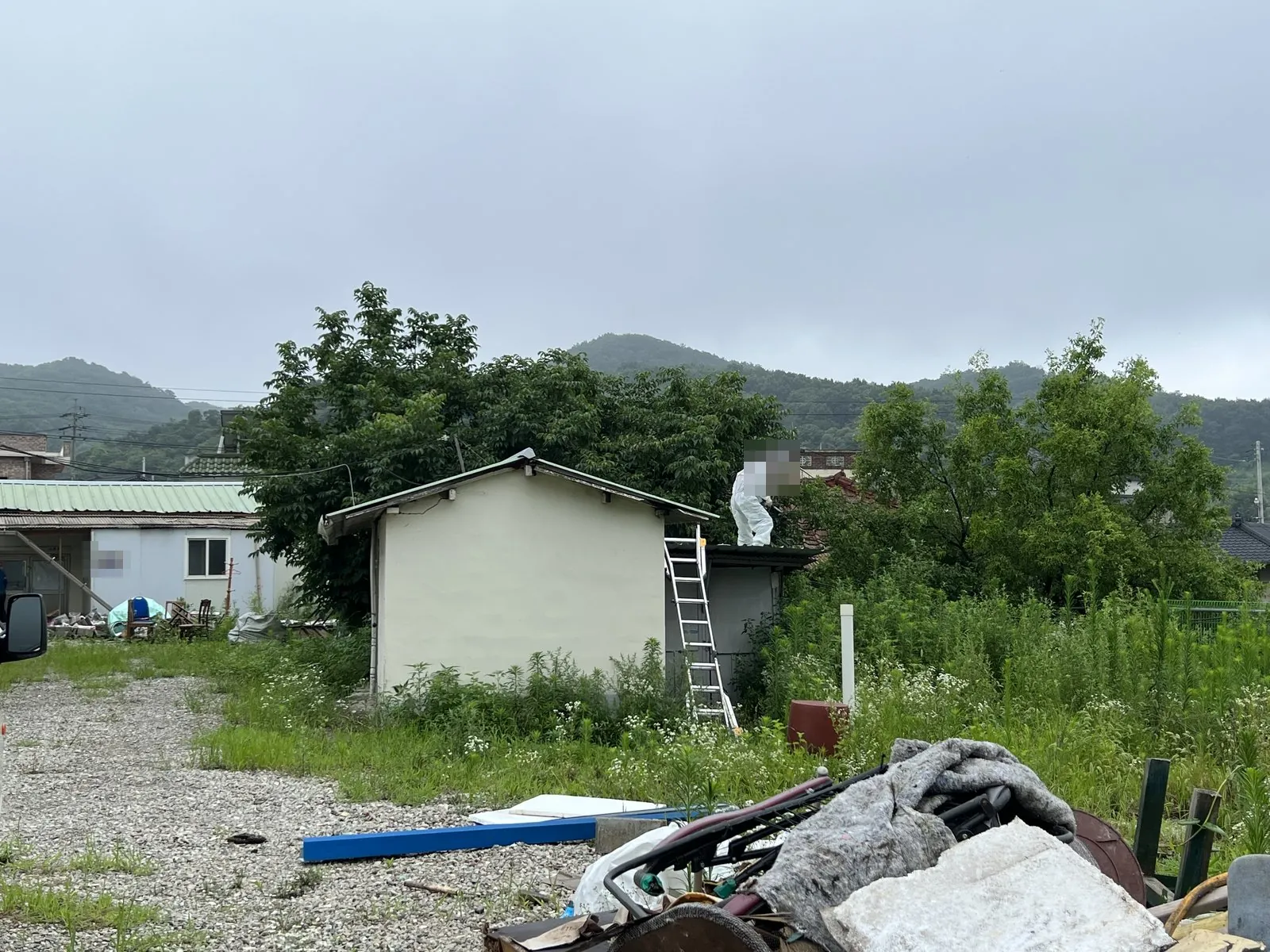 지붕 위 작업과 사다리, 앞쪽에 잔재가 쌓여 있음