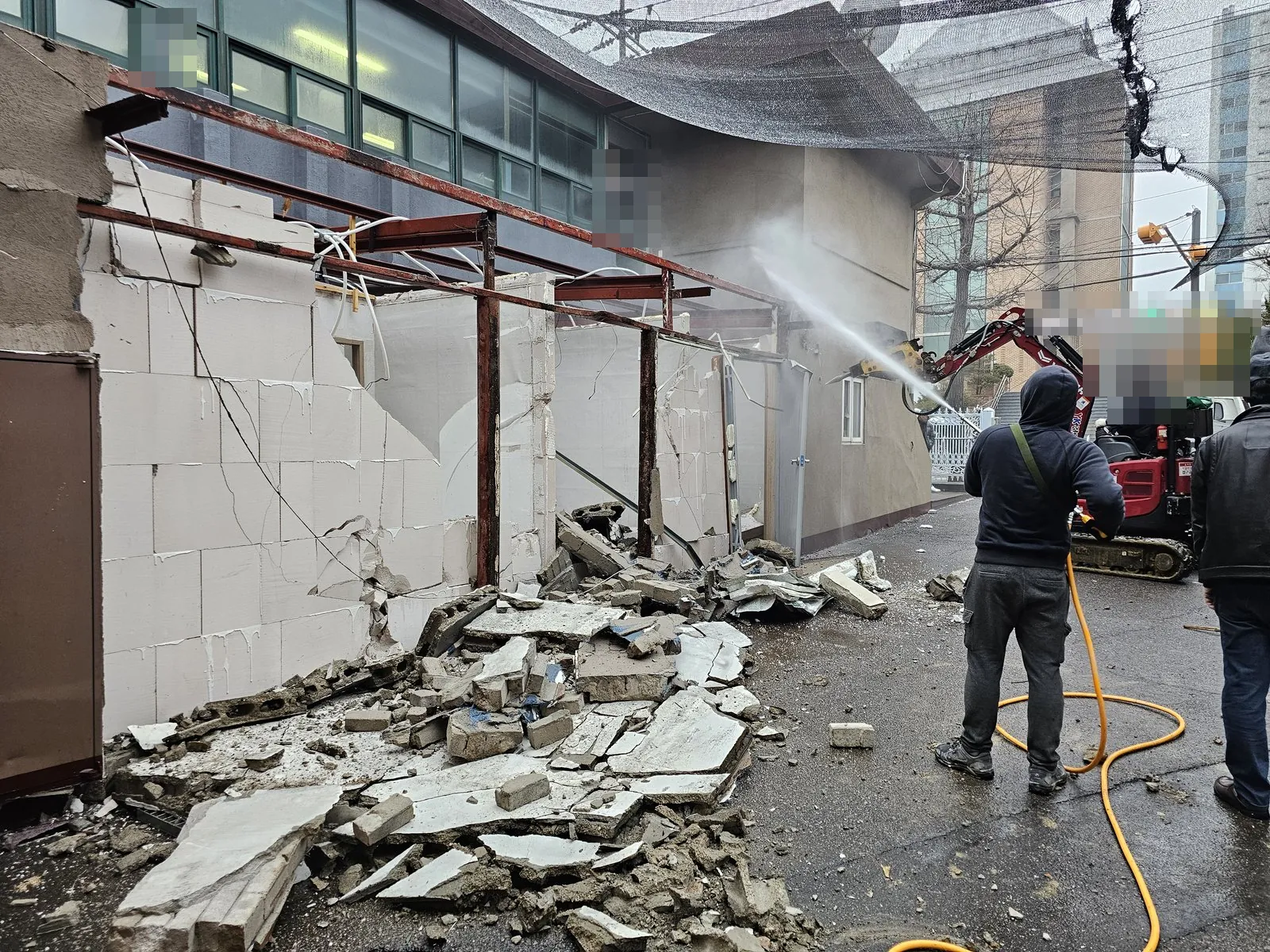 굴착기와 살수로 벽체를 해체하고 잔재가 쌓인 현장