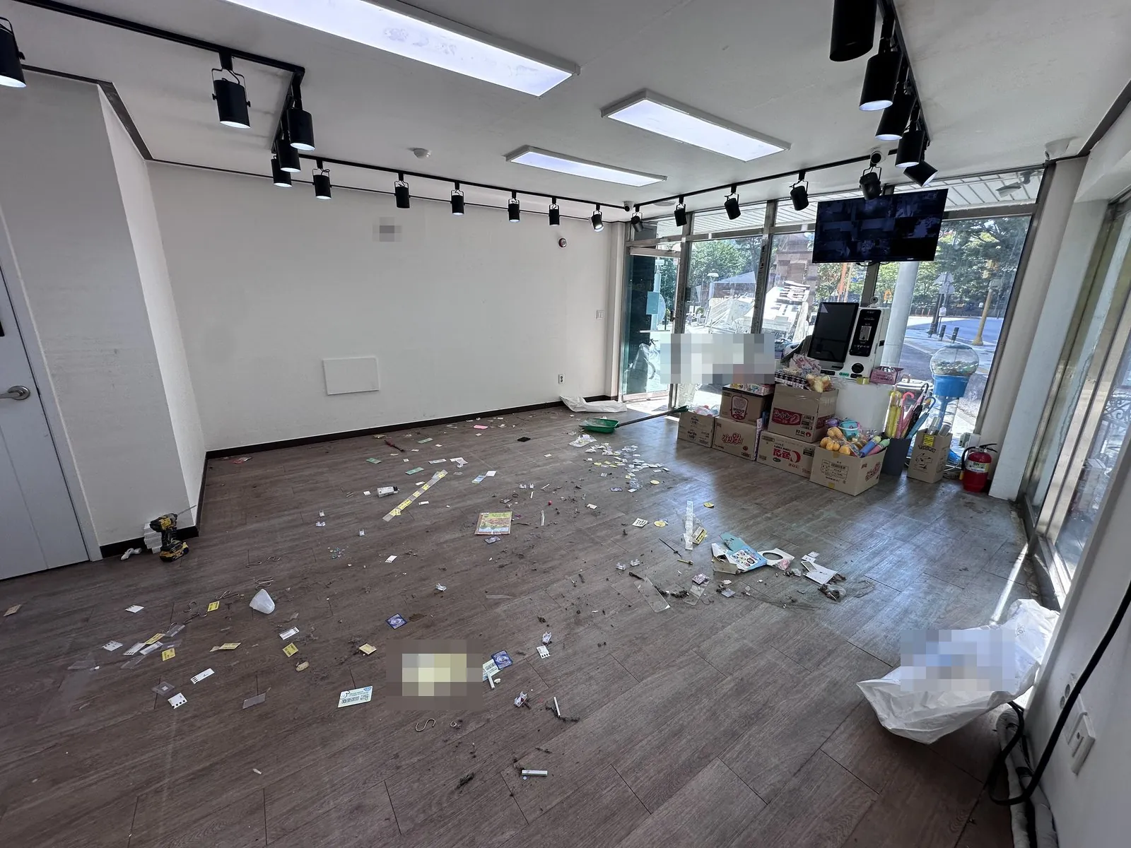 철거 중 매장 홀 바닥에 잔재가 흩어져 있고 빗자루로 정리한다.
