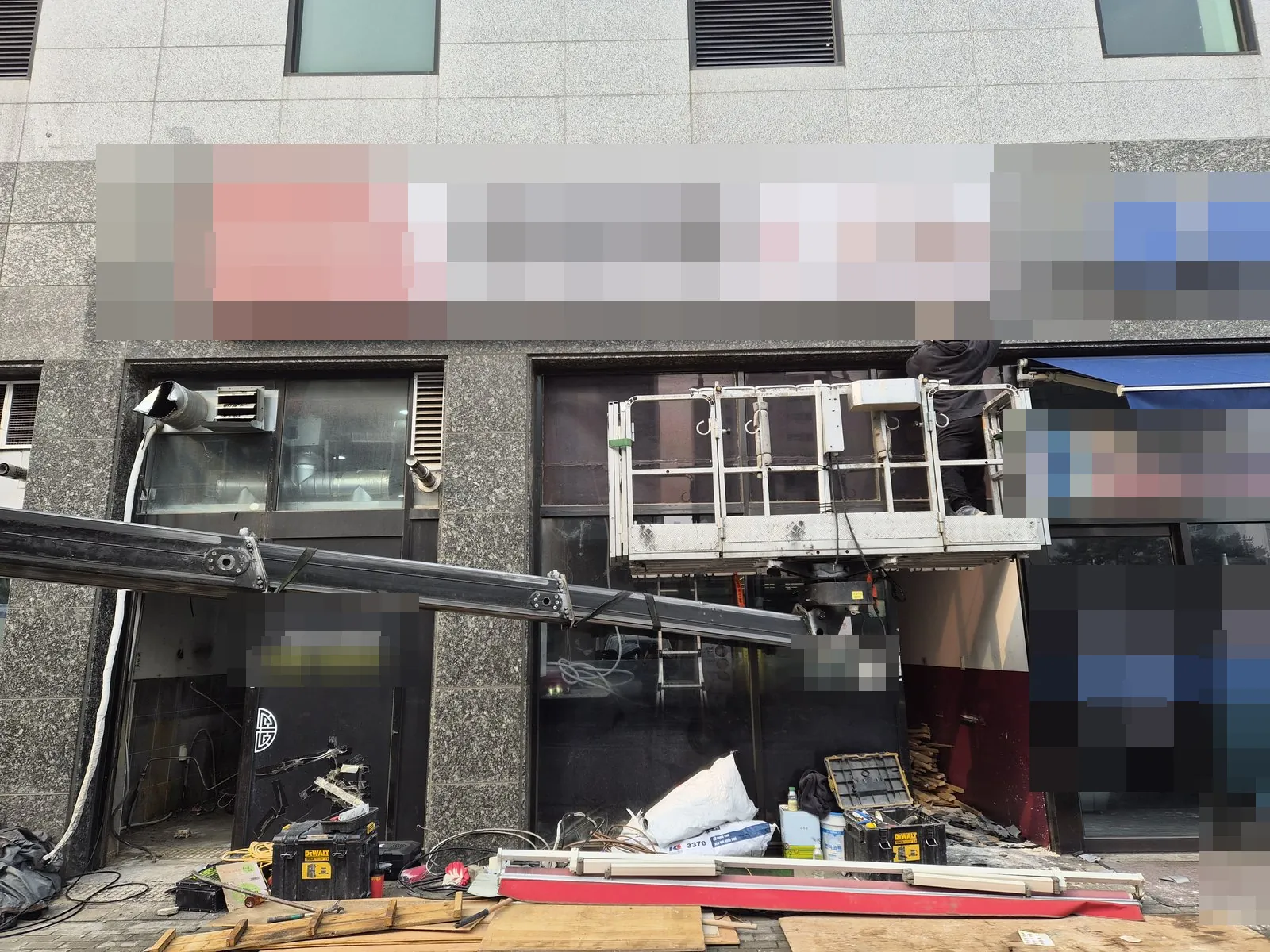 고소작업차 작업대에서 건물 전면 간판을 떼어내는 중