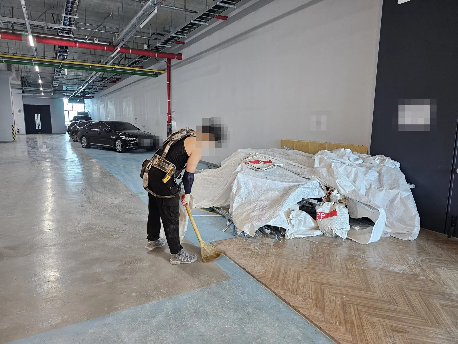 주차장 한켠에 마대로 덮은 잔재를 쌓고 바닥을 쓰는 정리 작업