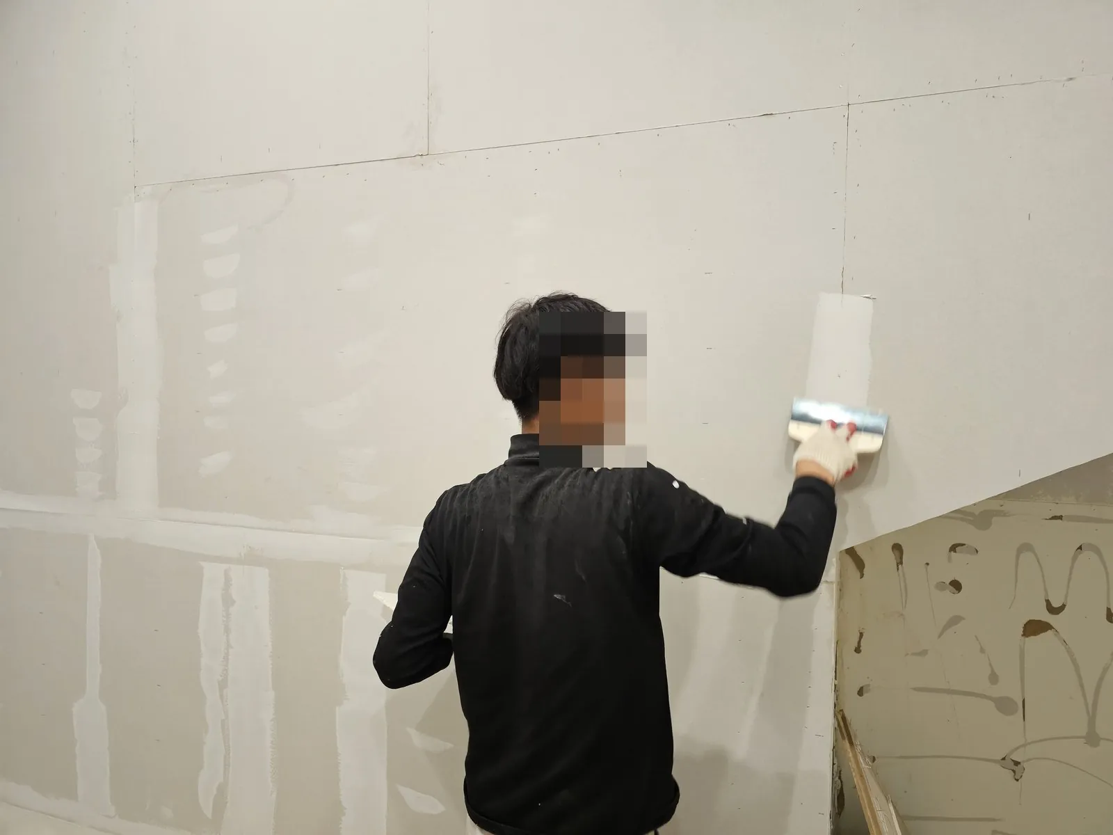 석고보드 벽 이음매에 퍼티 작업을 하고 있다.