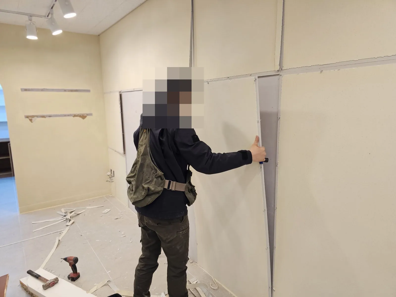 벽체 석고보드를 떼어내고 바닥에 조각과 공구가 놓여 있다.