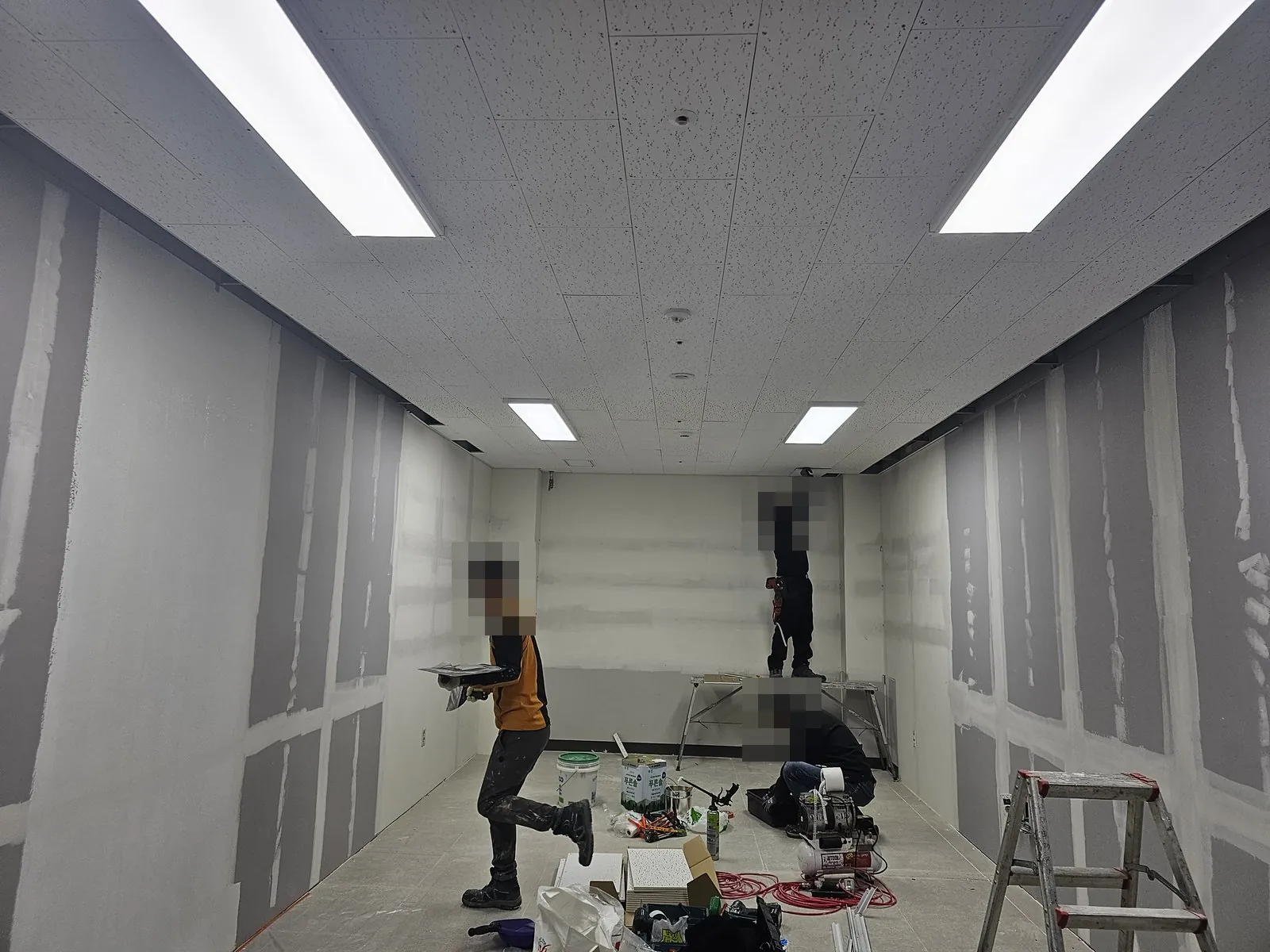 석고보드 벽 퍼티 작업과 천장 작업이 이뤄지는 실내, 공구와 자재가 놓임