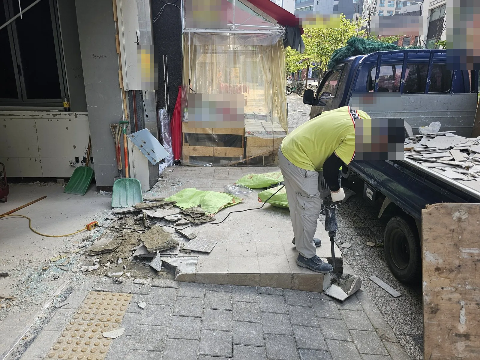 상가 출입구 앞 바닥 타일을 브레이커로 깨고 잔재를 화물차에 싣는 작업