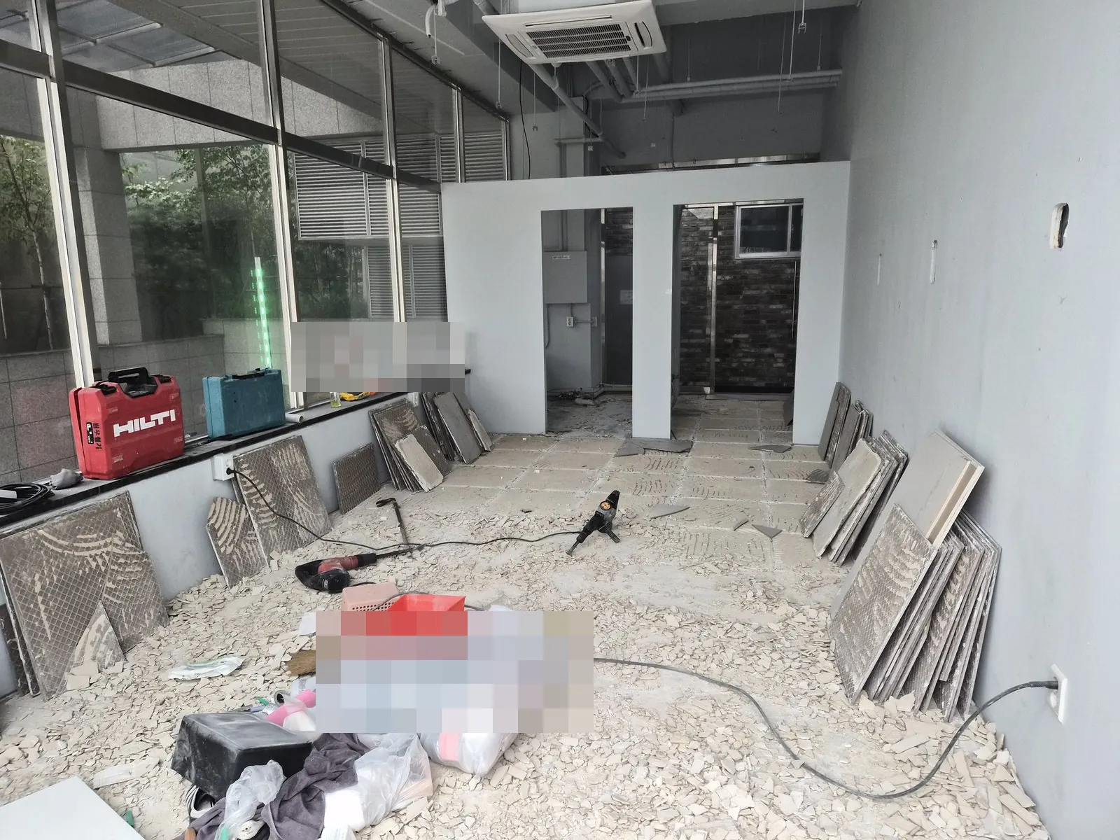 타일 조각이 깔린 바닥에 뜯은 타일과 마대가 쌓인 작업 중 매장