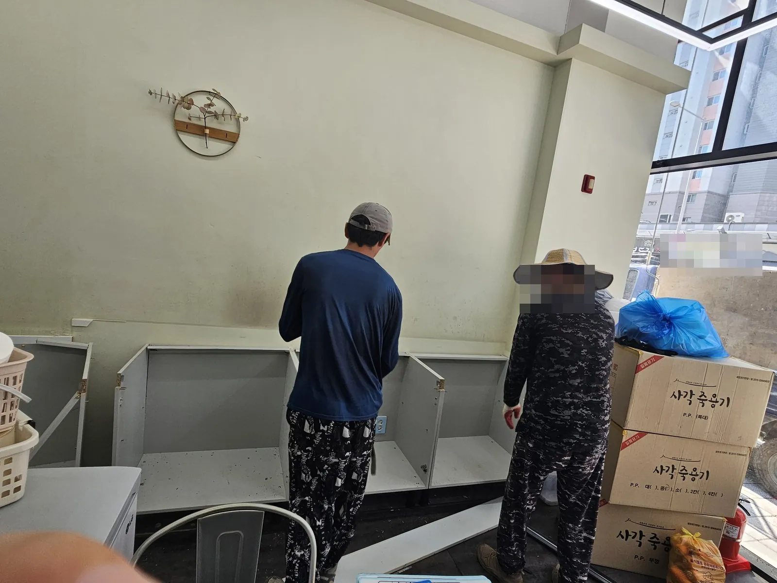 벽면 앞에서 하부장 싱크대 캐비닛을 해체하는 작업